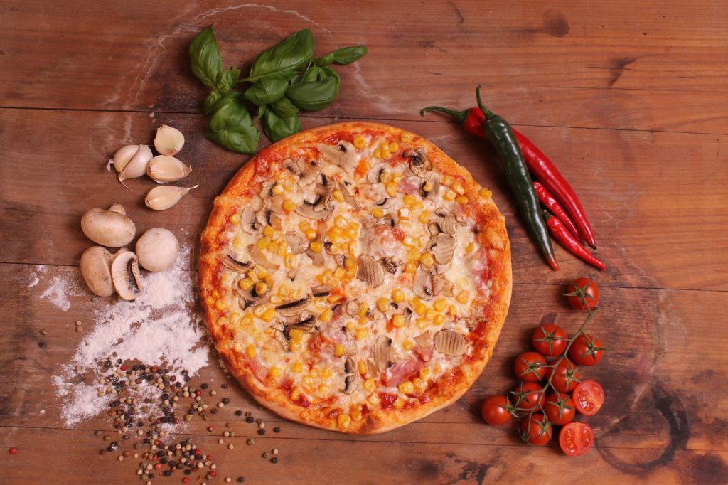 Gombás-kukoricás pizza felülről, fa deszkán